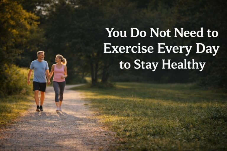 Middle-aged couple walking on a park path during sunset with the title “You Do Not Need to Exercise Every Day to Stay Healthy.”