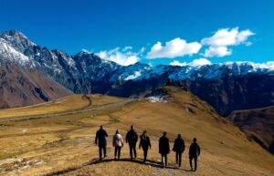 Group of people walking toward a hilltop church with snowy mountains in the background