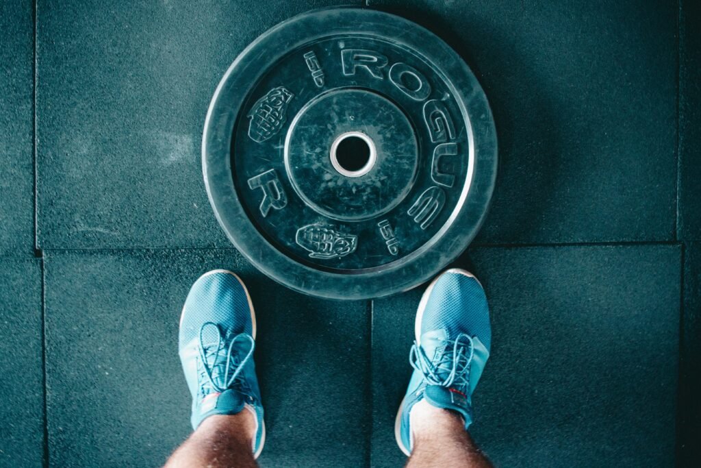 op view of gym shoes next to a weight plate on rubber flooring