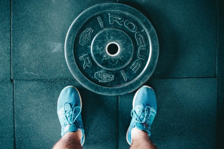 op view of gym shoes next to a weight plate on rubber flooring