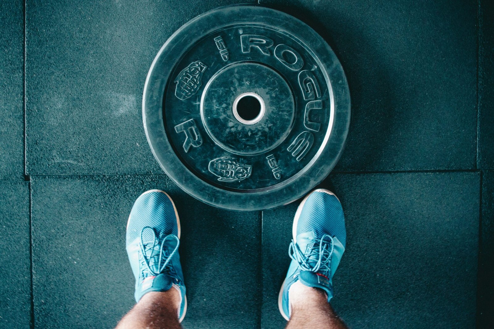 op view of gym shoes next to a weight plate on rubber flooring