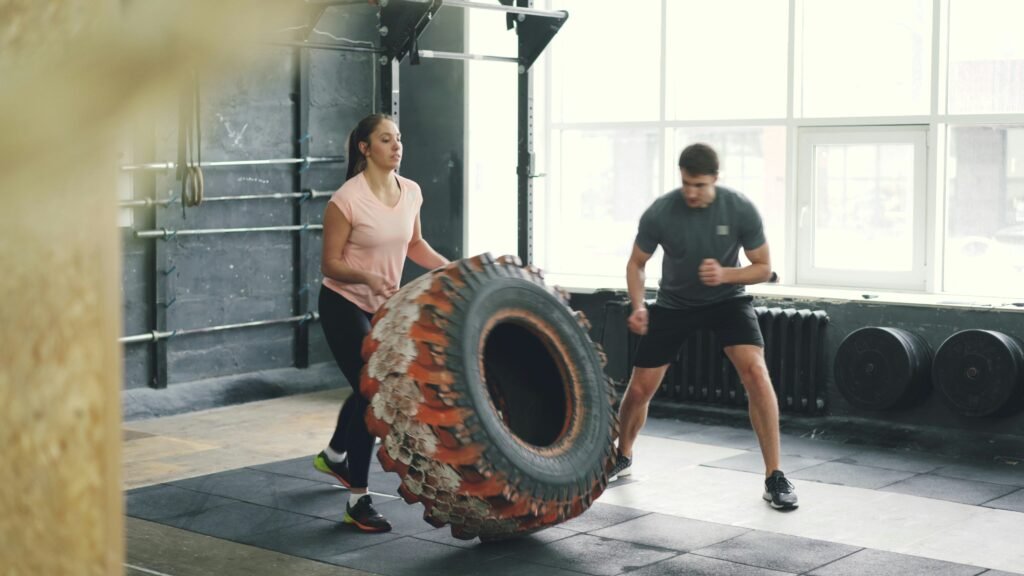 Two people flipping a large tire during a workout in a gym