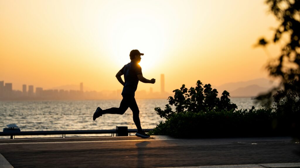 A person running along the water during sunset