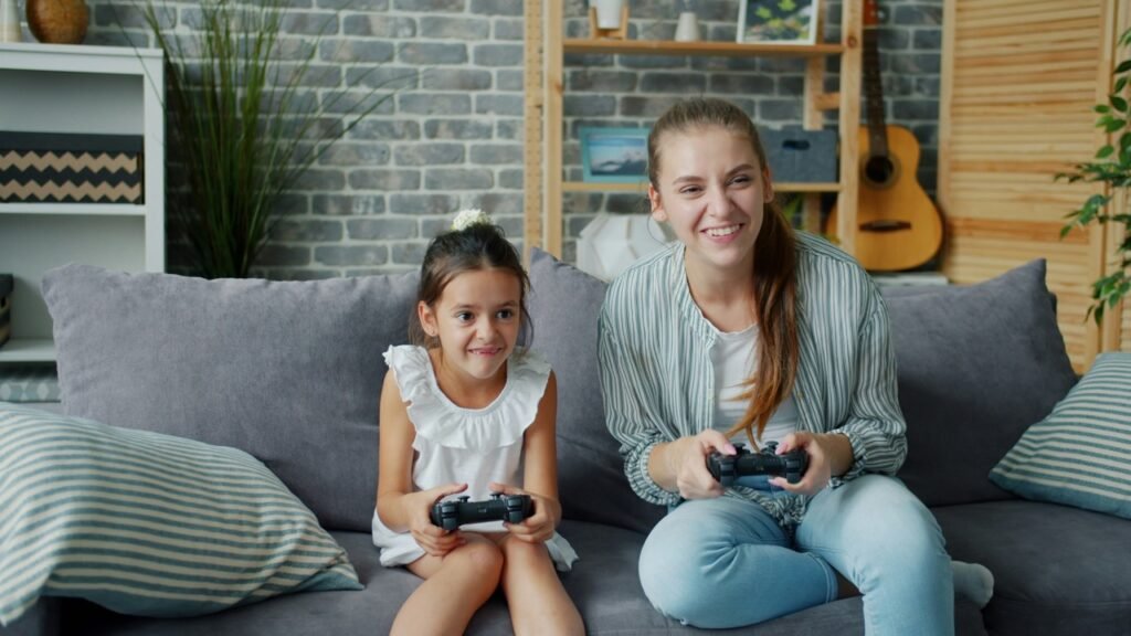 A mother and young child playing video games together on a couch