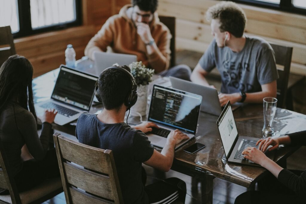 Team of professionals working together on laptops during a collaborative office meeting, highlighting human skills such as communication, teamwork, and problem-solving in the AI workplace.