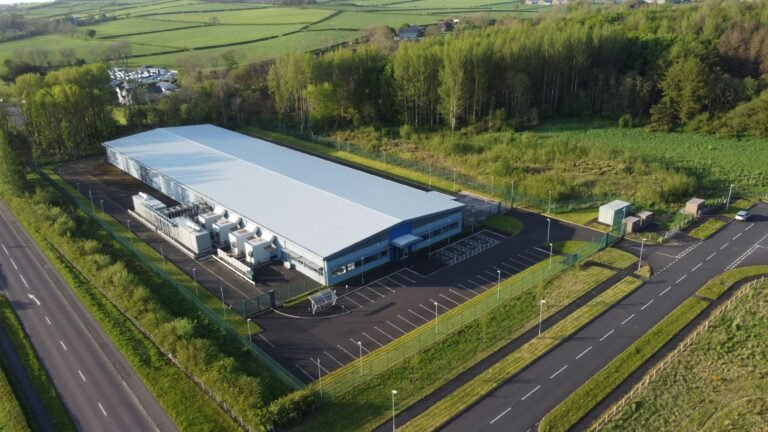 Large modern data center building surrounded by roads, trees, and green countryside viewed from above.