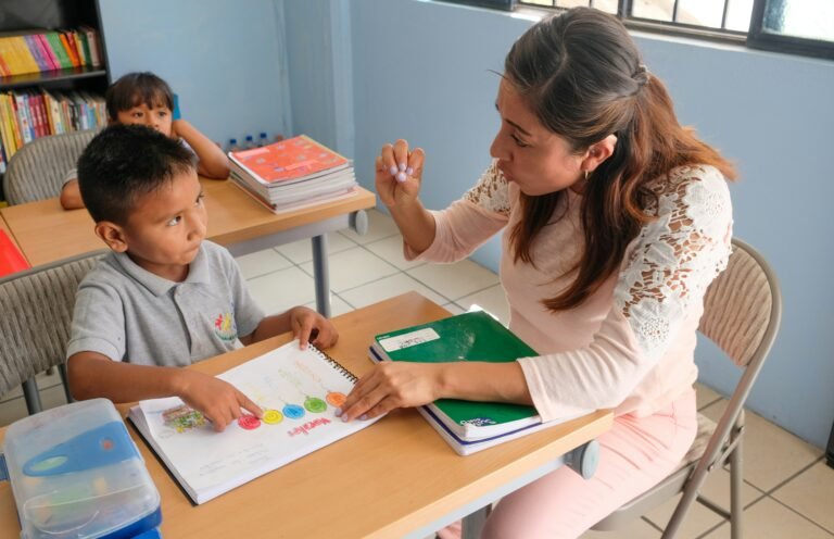 ESL teacher helping a young student develop speaking and communication skills during an interactive classroom lesson.
