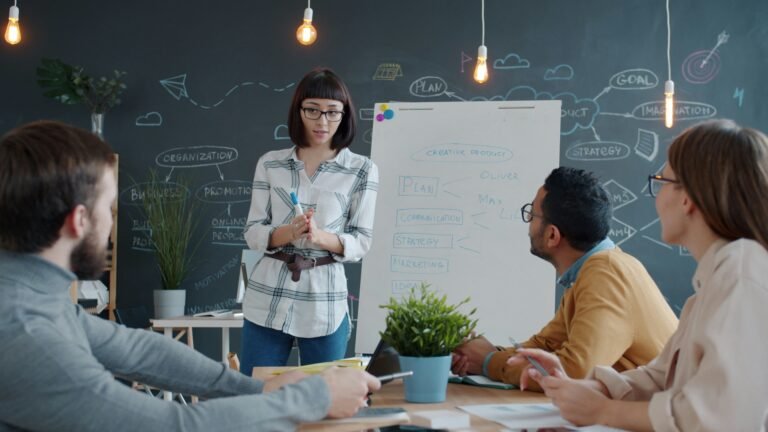 Professional leading a team meeting while presenting ideas on a whiteboard, demonstrating collaboration, communication, and skill development in the workplace.