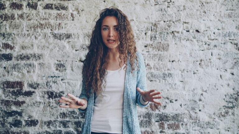 A woman speaking with an expressive facial expression and hand gestures, representing the importance of tone, communication, and choosing words carefully.
