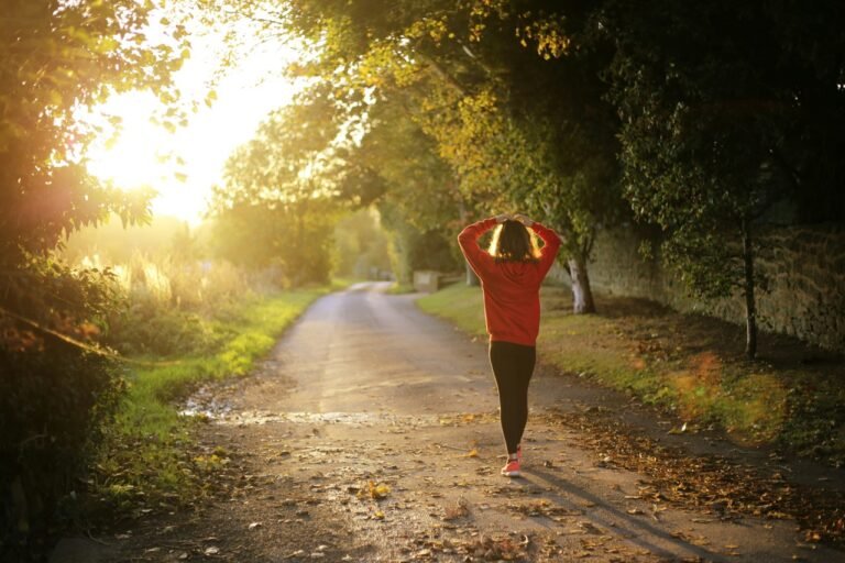 Person walking along a quiet country road during a sunny morning for exercise.