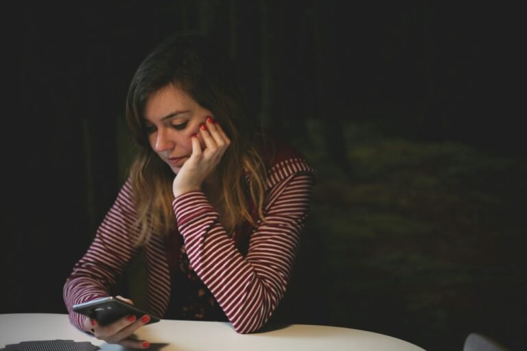 Person sitting scrolling phone in the dark, unable to sleep — revenge bedtime procrastination