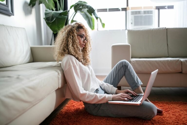 A woman sitting on the floor typing on her laptop, engaged in conversation with an AI chatbot