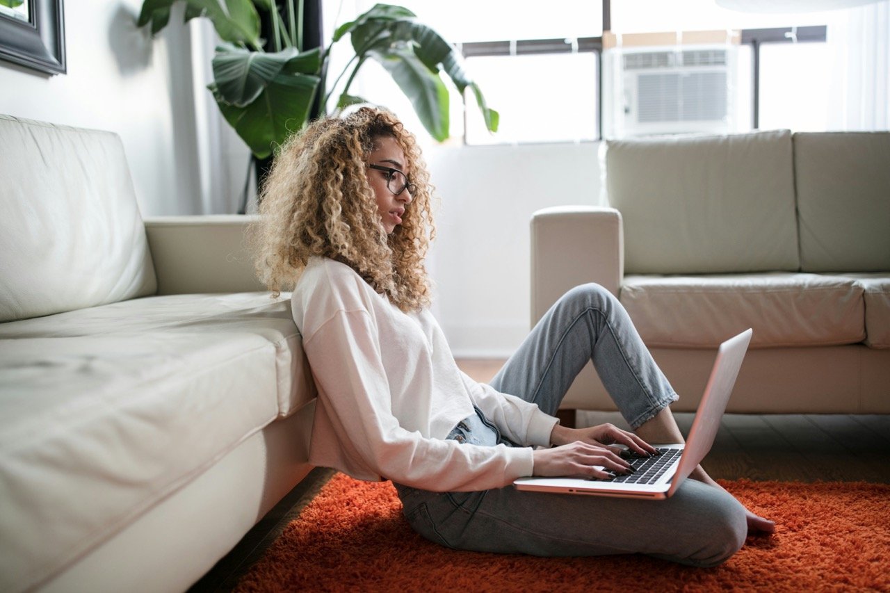 A woman sitting on the floor typing on her laptop, engaged in conversation with an AI chatbot