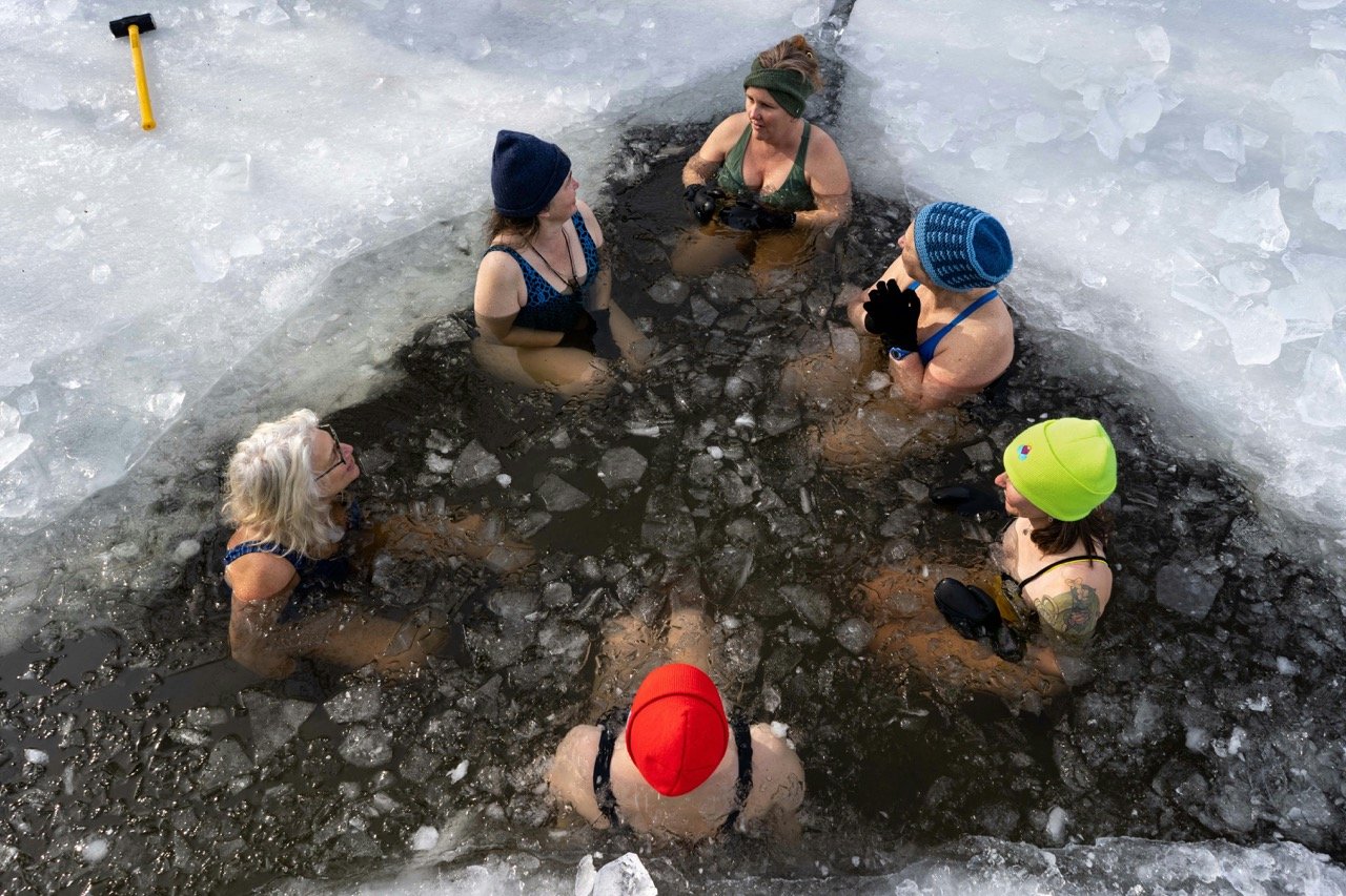 People taking an ice bath in a frozen lake