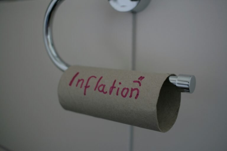 Empty toilet paper roll with "inflation" written on it in marker, hanging on a holder