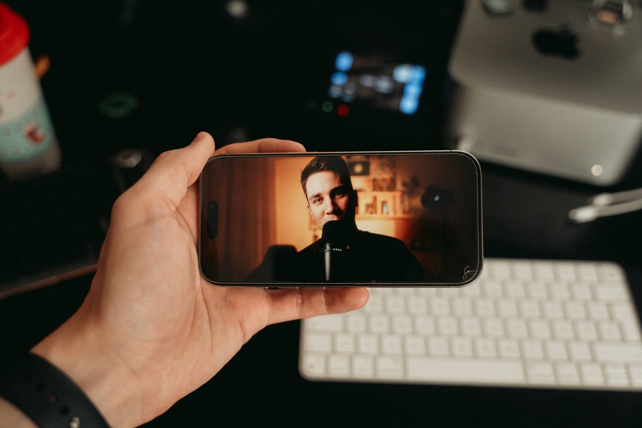 A person holds a smartphone while watching a content creator, illustrating the growing influence of parasocial relationships and online creators.