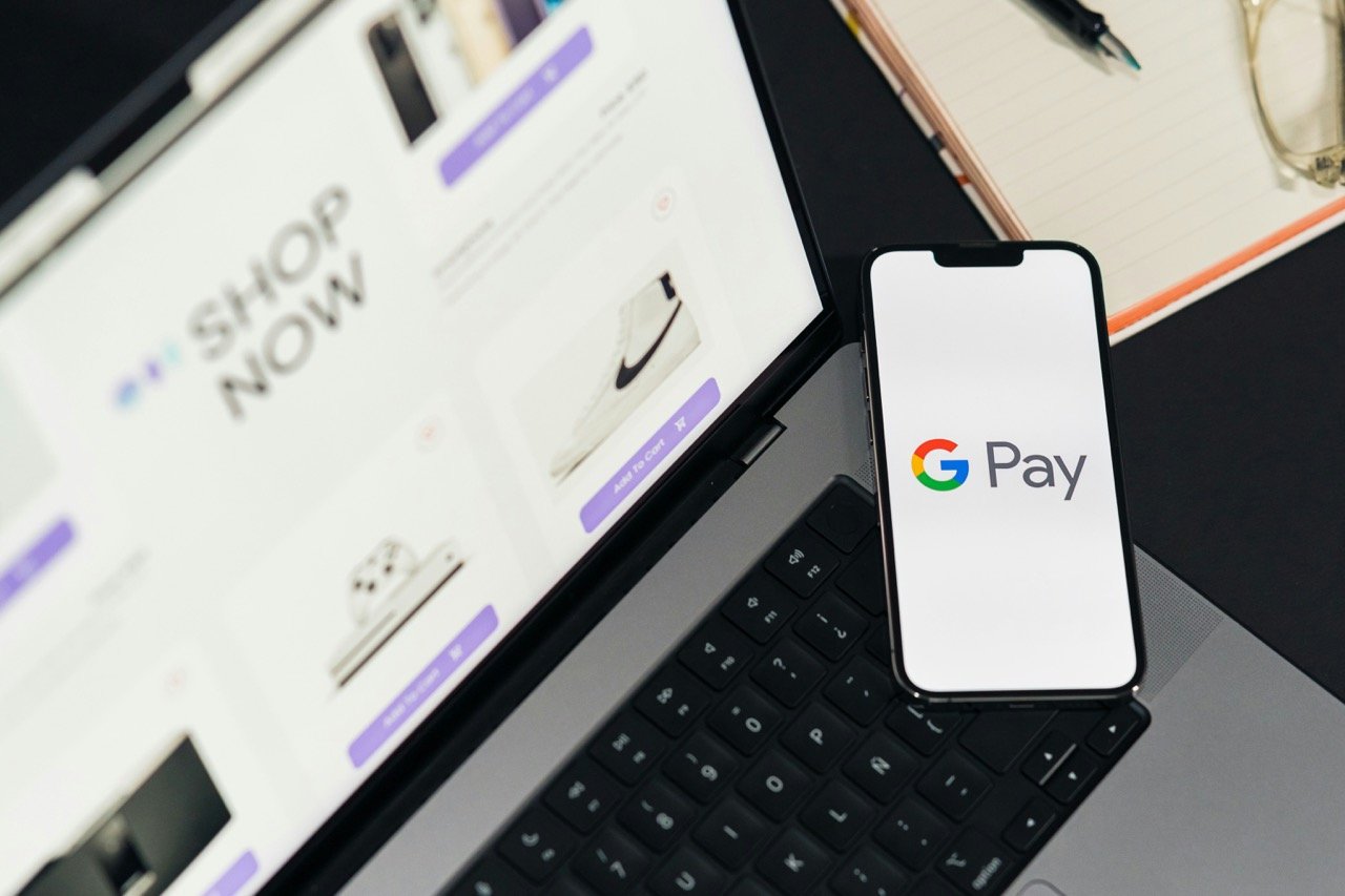 Smartphone showing Google Pay beside a laptop used for online shopping