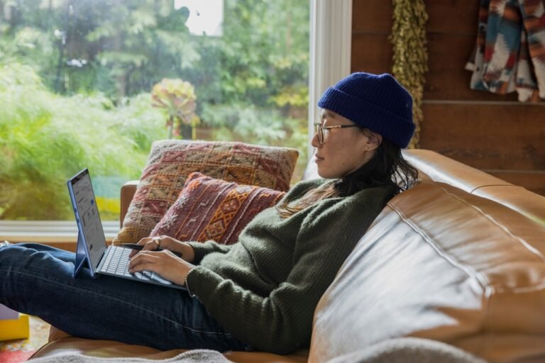 Woman working alone on a couch at home, illustrating the isolation of remote work