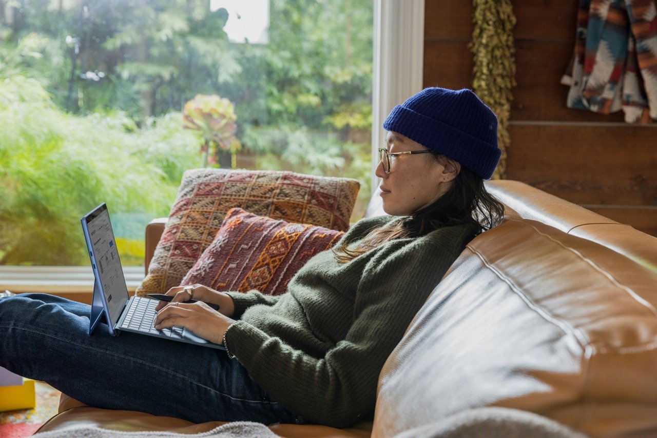 Woman working alone on a couch at home, illustrating the isolation of remote work