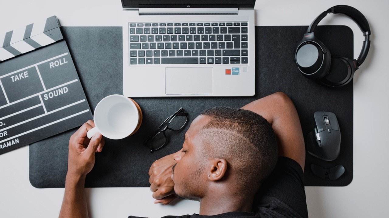 Tired employee resting at a desk beside a laptop and coffee