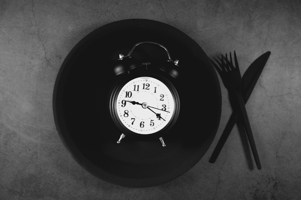 Alarm clock and empty plate representing fasting and meal timing