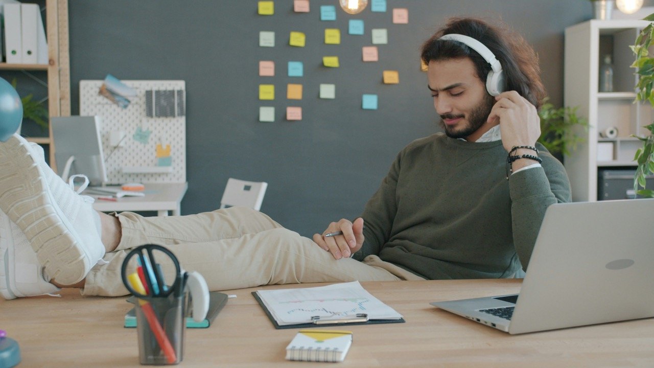 Man working at a desk with headphones and a laptop