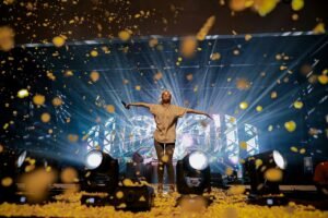 Singer performing on stage as confetti falls during a live concert